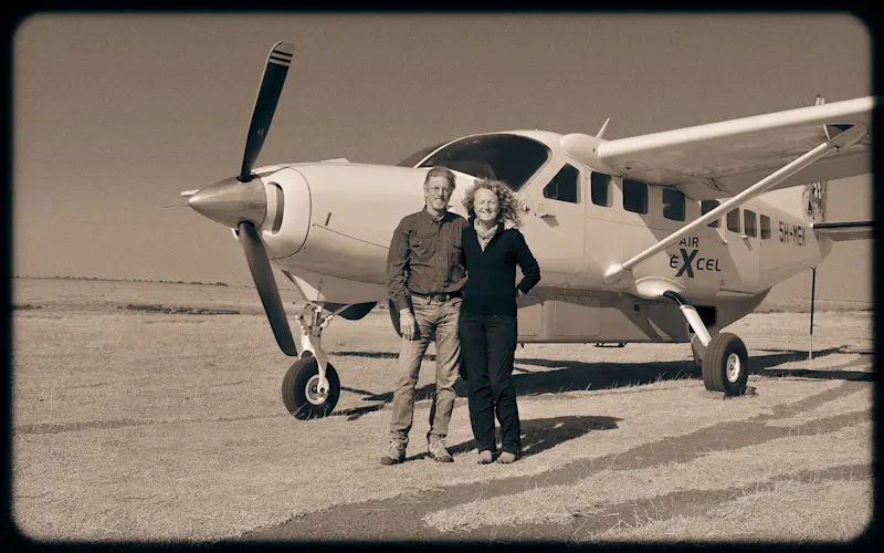 Sepia photo of Rick Thomson and Judi Wineland standing in front of a small propeller plane
