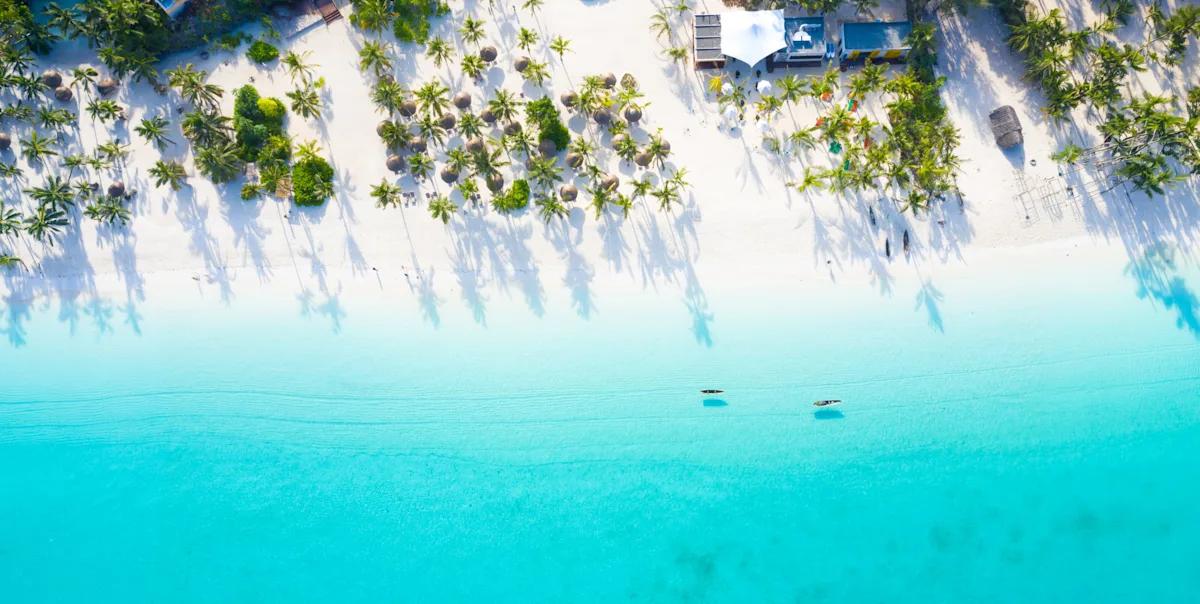 Aerial view of a white sand beach, palm trees and turquoise water on Zanzibar