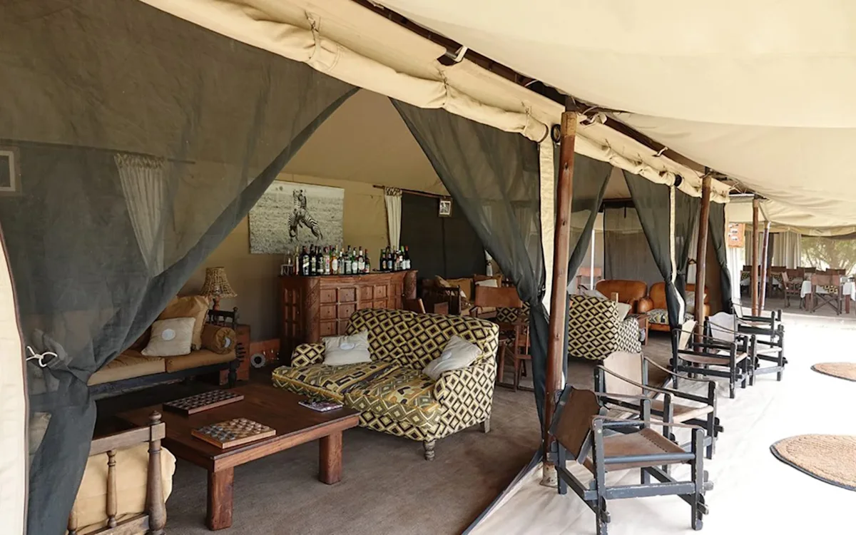 Lounge tent with patterned sofas, a game table and a bar at Eastern Serengeti Nyumba