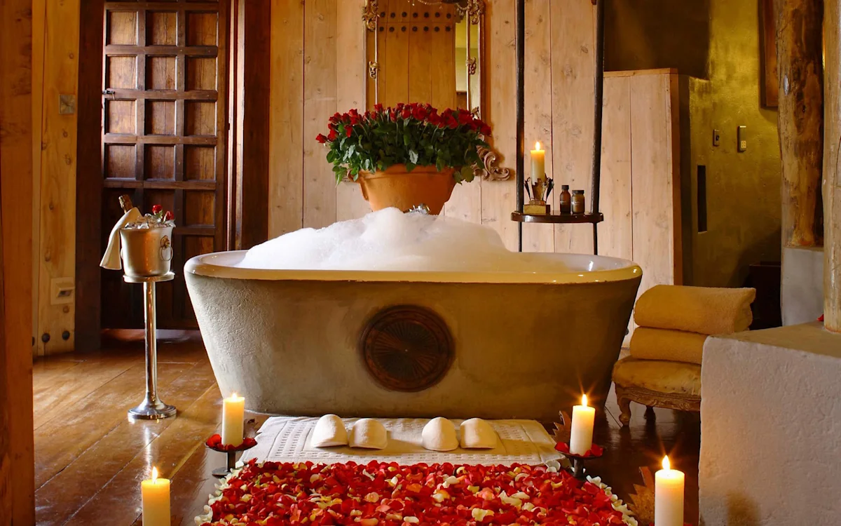 Freestanding bubble bath surrounded by candles and rose petals in a safari lodge suite