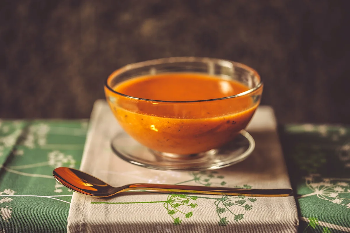 Glass bowl of carrot ginger soup on a linen napkin
