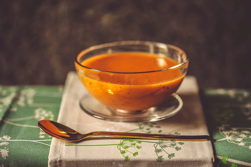 Glass bowl of carrot ginger soup on a linen napkin