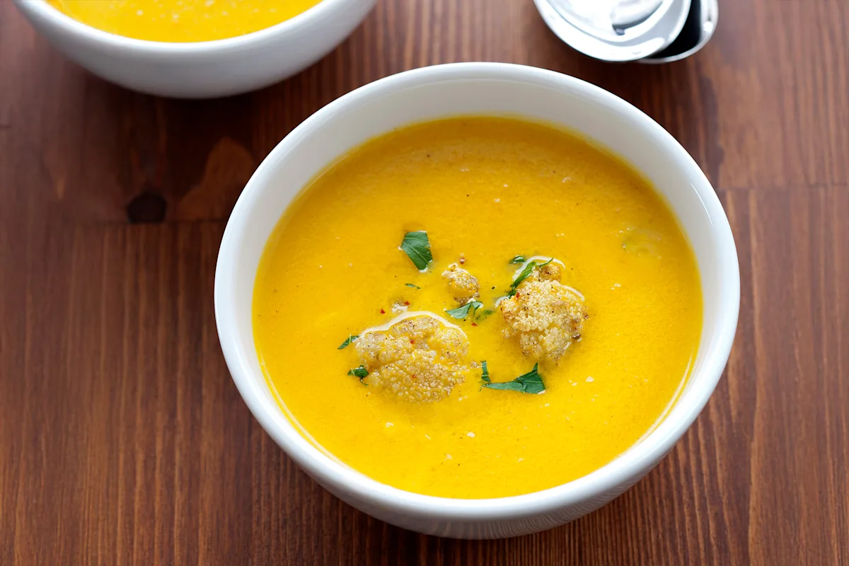 Bowl of chicken curry soup garnished with herbs