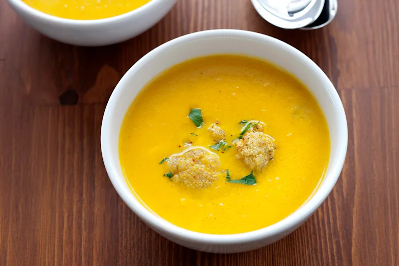 Bowl of chicken curry soup garnished with herbs