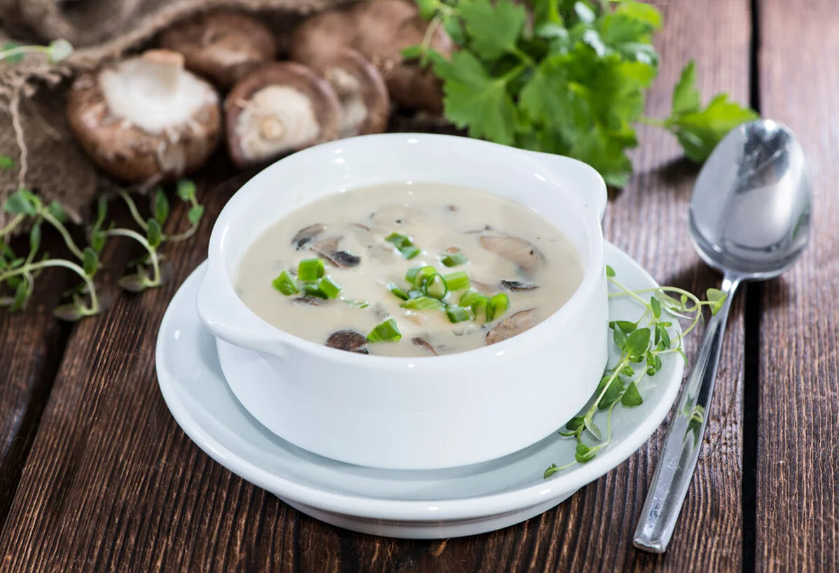 Bowl of creamy coconut soup with mushrooms and herbs