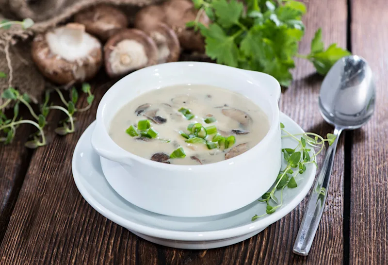 Bowl of creamy coconut soup with mushrooms and herbs