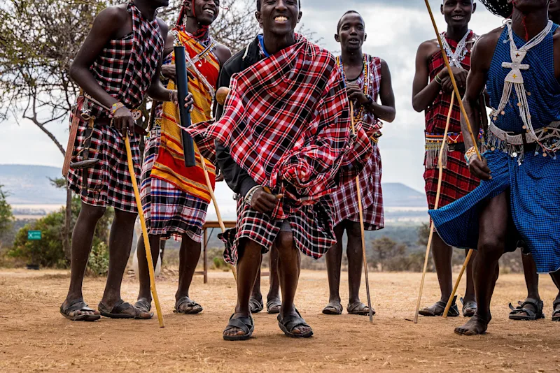Maasai men in traditional shukas holding walking sticks