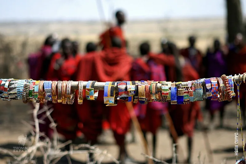 Beaded Maasai bracelets displayed in front of Maasai people in red shukas