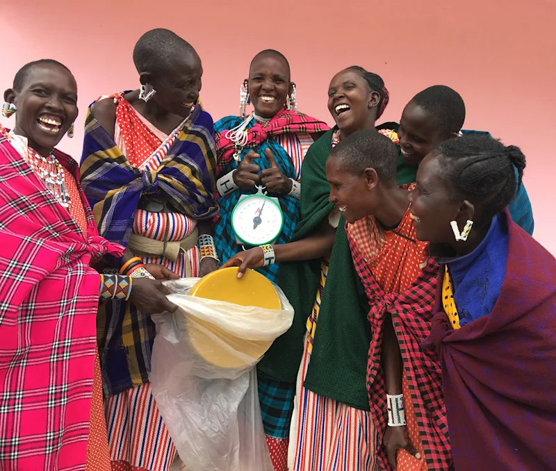 Smiling Maasai women of a FOTZC beekeeping group gathered around a scale
