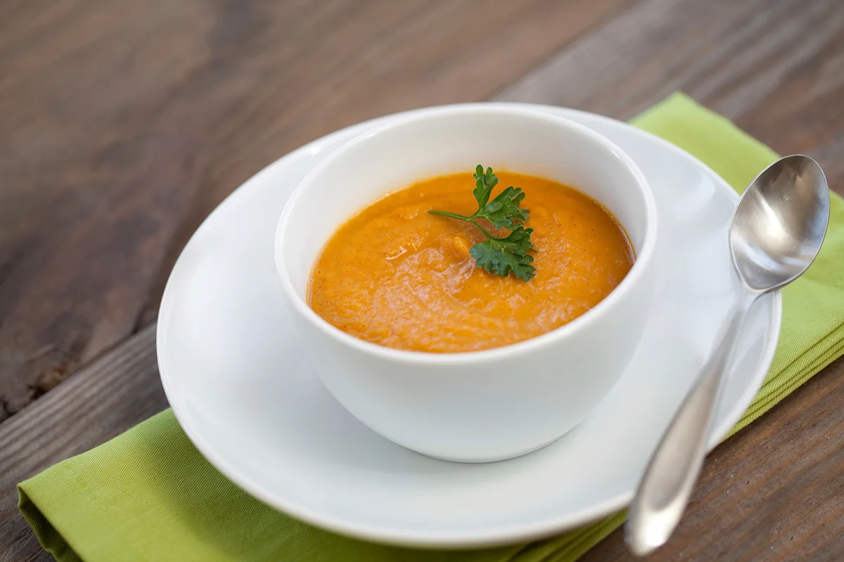 Bowl of pumpkin and sweet potato soup garnished with parsley