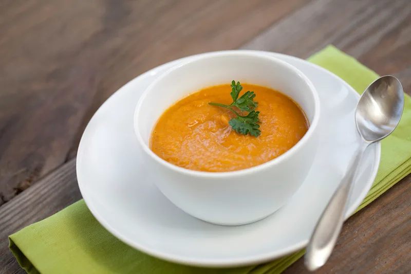 Bowl of pumpkin and sweet potato soup garnished with parsley