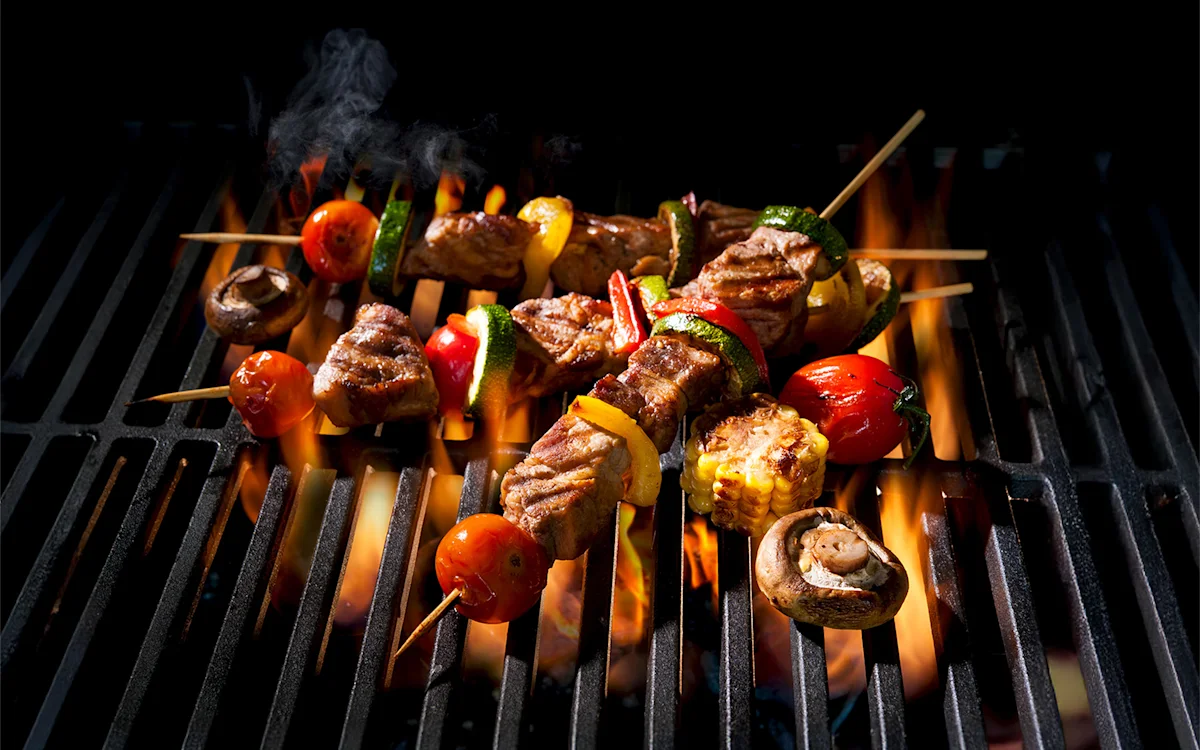 Skewers of meat and vegetables grilling over an open flame