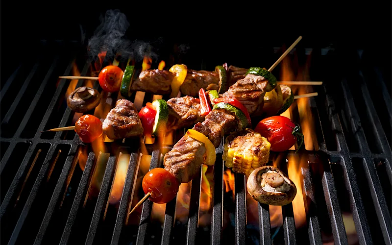 Skewers of meat and vegetables grilling over an open flame