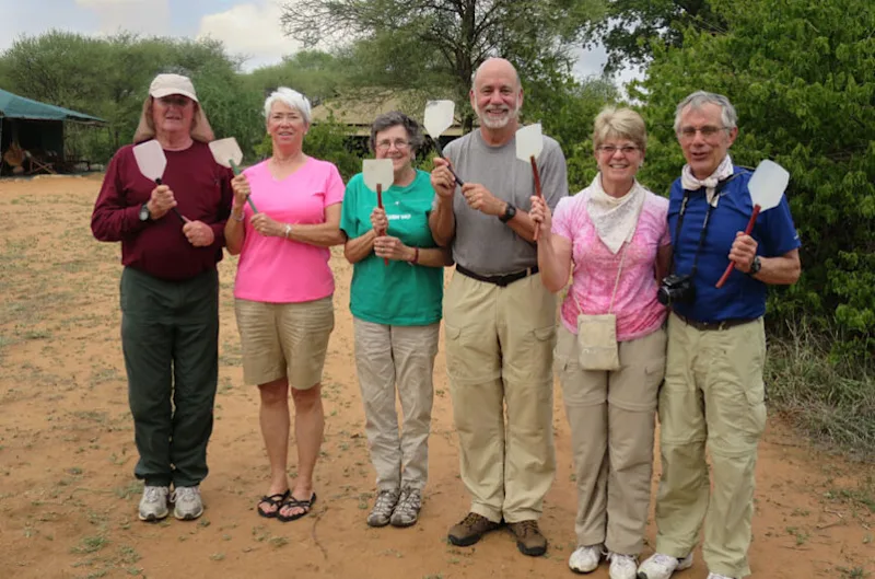 Thomson Safaris guests holding up fly swatters at camp