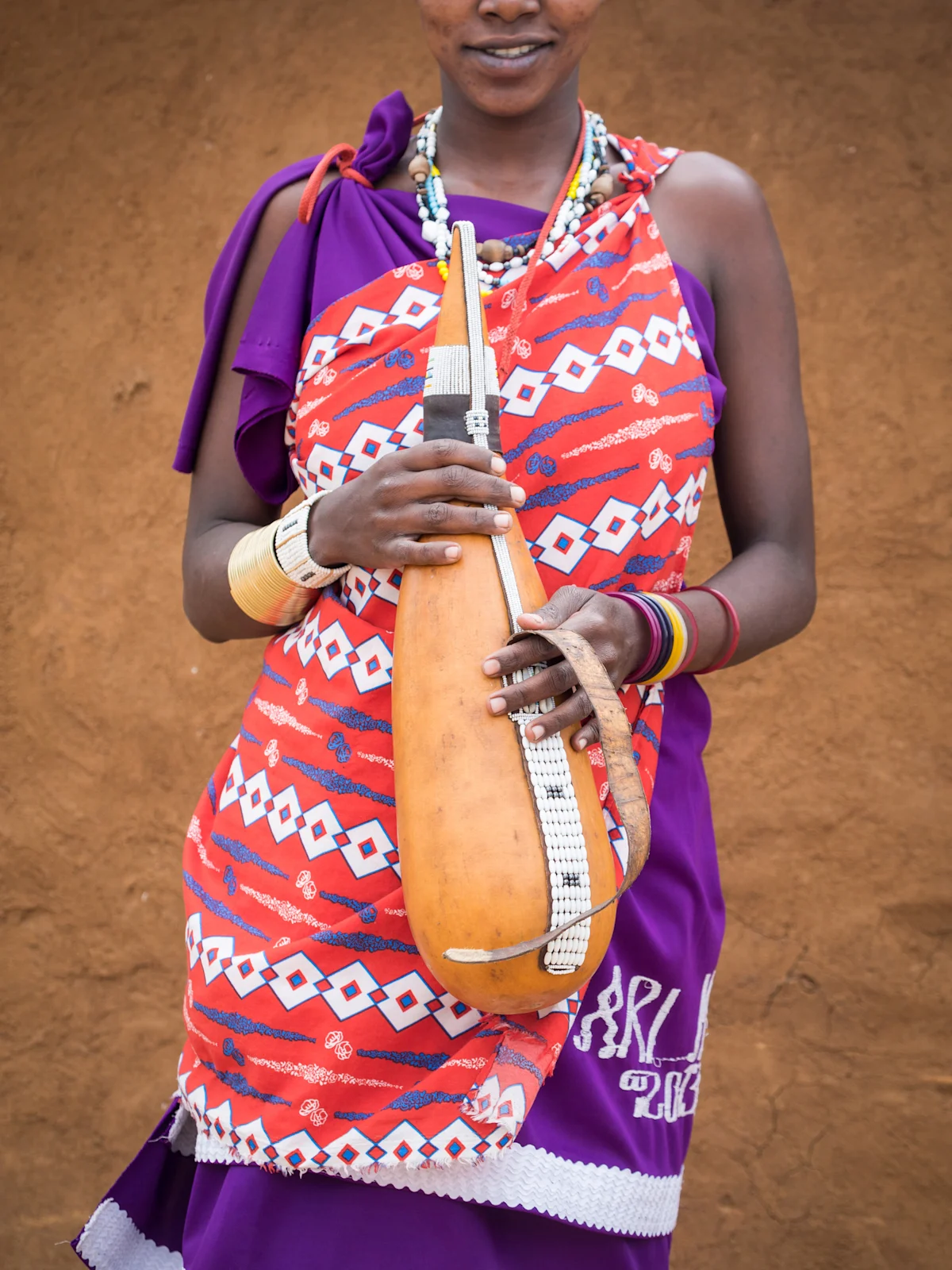 Maasai woman in a beaded collar holding a decorated milk gourd