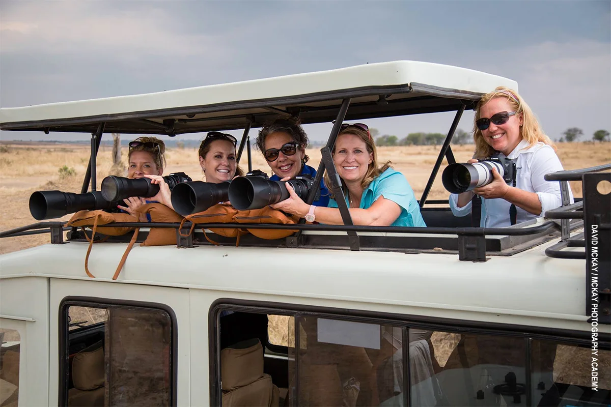 Photographers with long-lens cameras in the pop-up roof of a safari vehicle