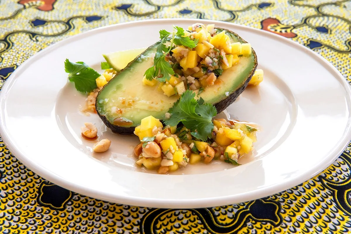 Avocado half topped with mango chutney and cilantro on a plate