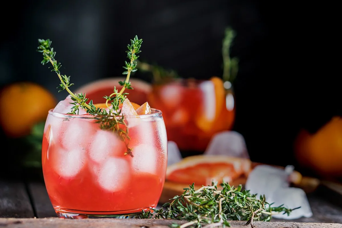 Cranberry gin and tonic over ice garnished with thyme sprigs