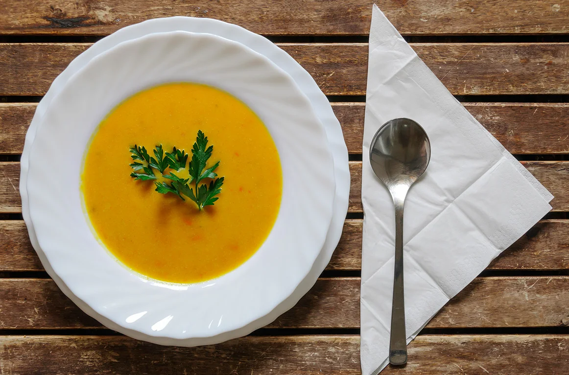 Bowl of pumpkin coconut soup garnished with parsley