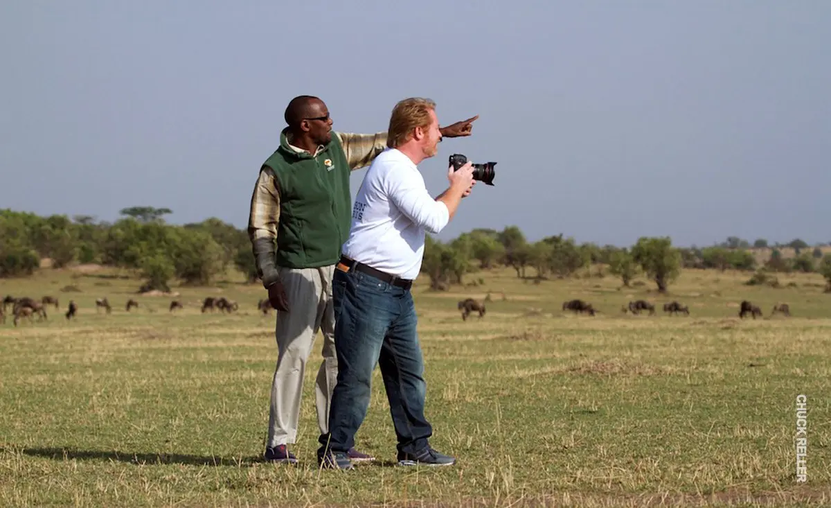 Thomson guide pointing out wildlife to a guest with a camera on the plains