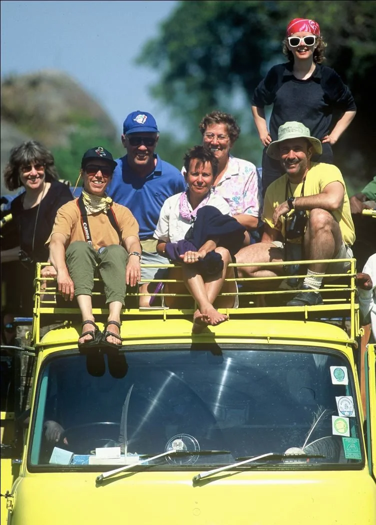 Group of travelers sitting on top of a yellow safari truck on the first safari in 1981