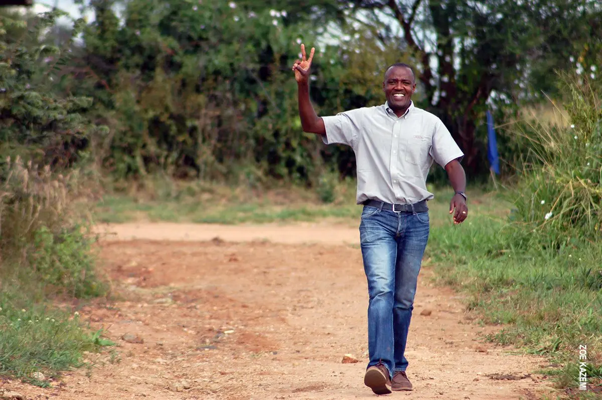 Smiling Thomson guide making a peace sign while walking along a dirt road