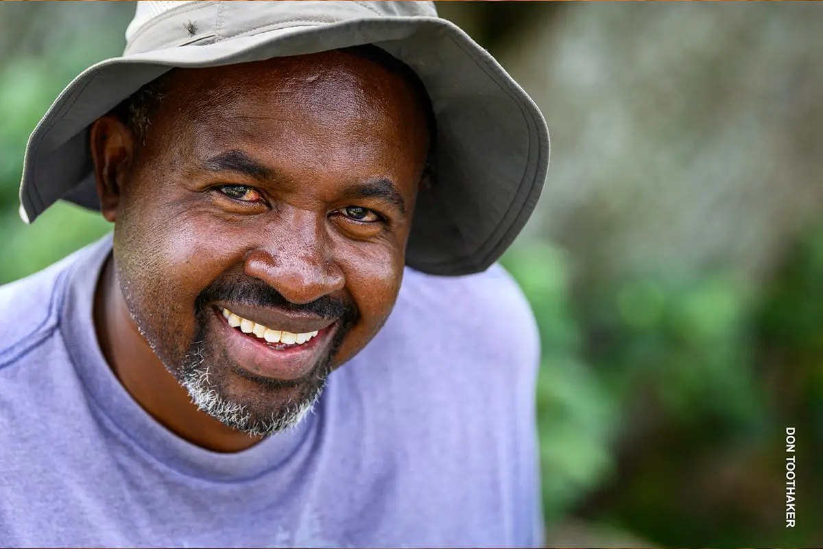 Close-up portrait of a smiling Thomson guide in a bucket hat