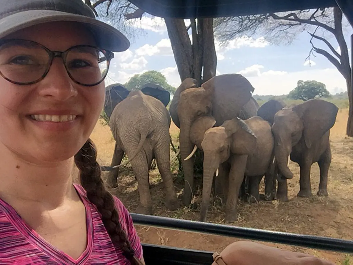 Thomson staff member taking a selfie with an elephant family behind her