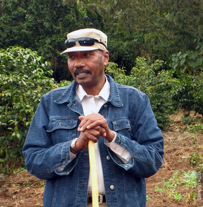 Early Thomson guide in a cap and denim jacket leaning on a walking stick