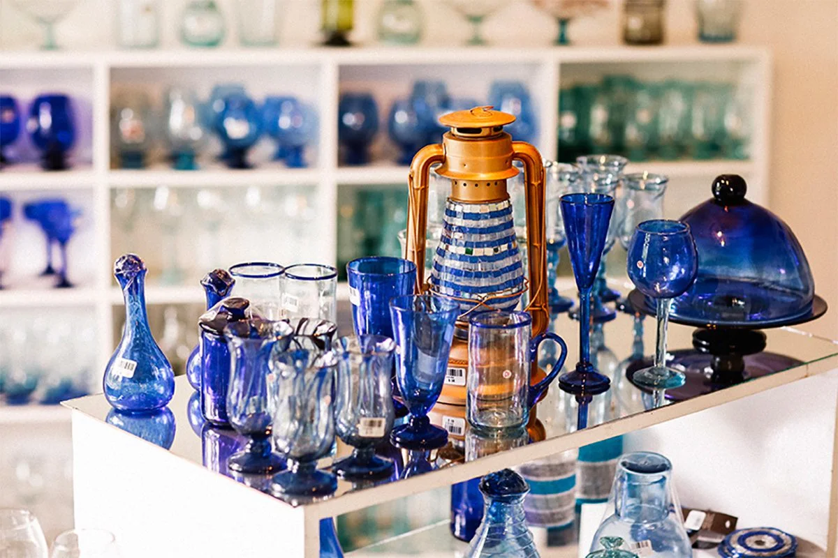 Blue handblown glassware and a beaded lantern displayed on a shop shelf