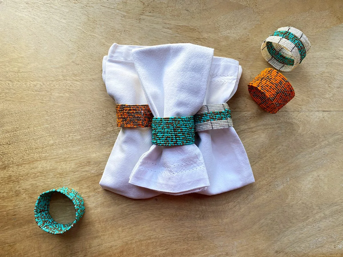 White napkins in beaded napkin rings of orange, turquoise and white