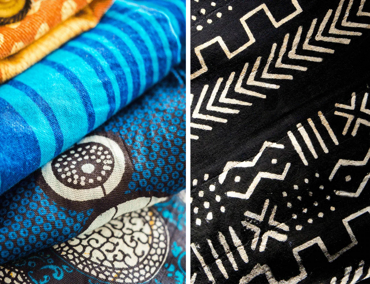 Folded African print fabrics in blue and orange beside a black and white mud cloth