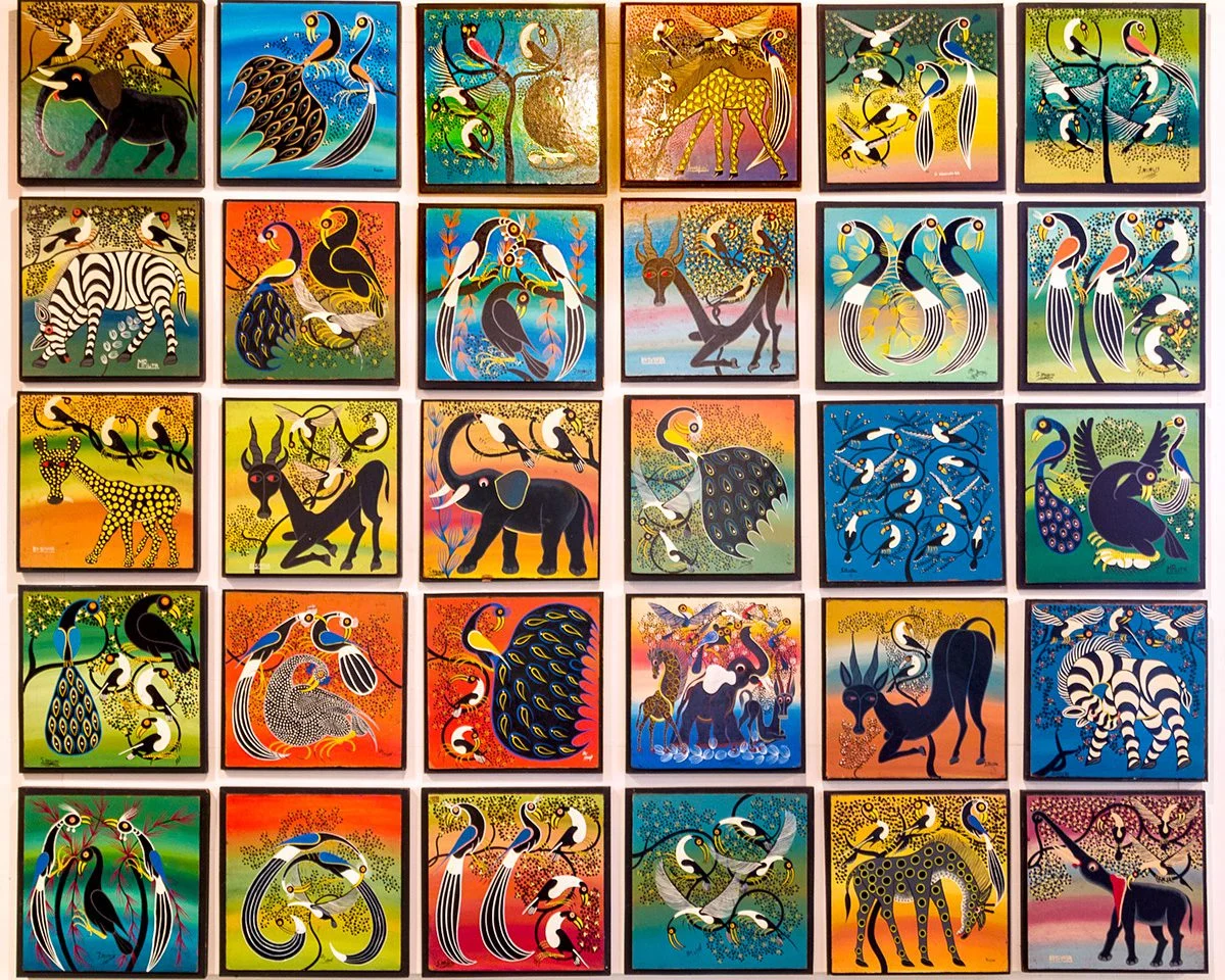 Wall of colorful Tingatinga paintings of birds, zebras, elephants and other animals