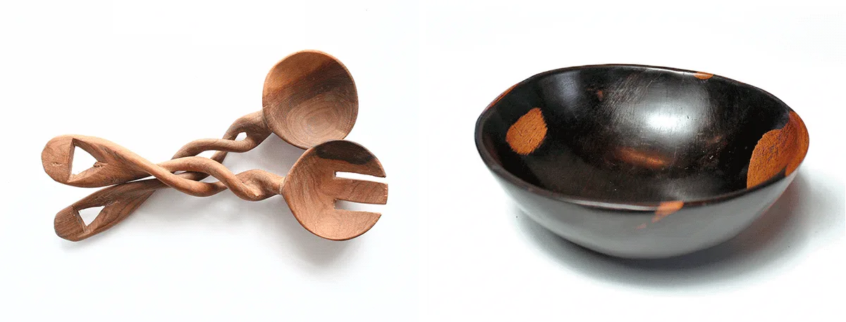 Carved wooden salad servers with twisted handles beside a dark wooden bowl