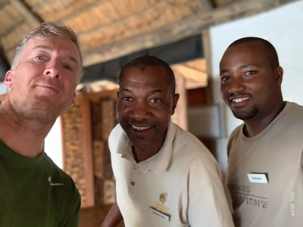 Traveler taking a selfie with two smiling camp staff members