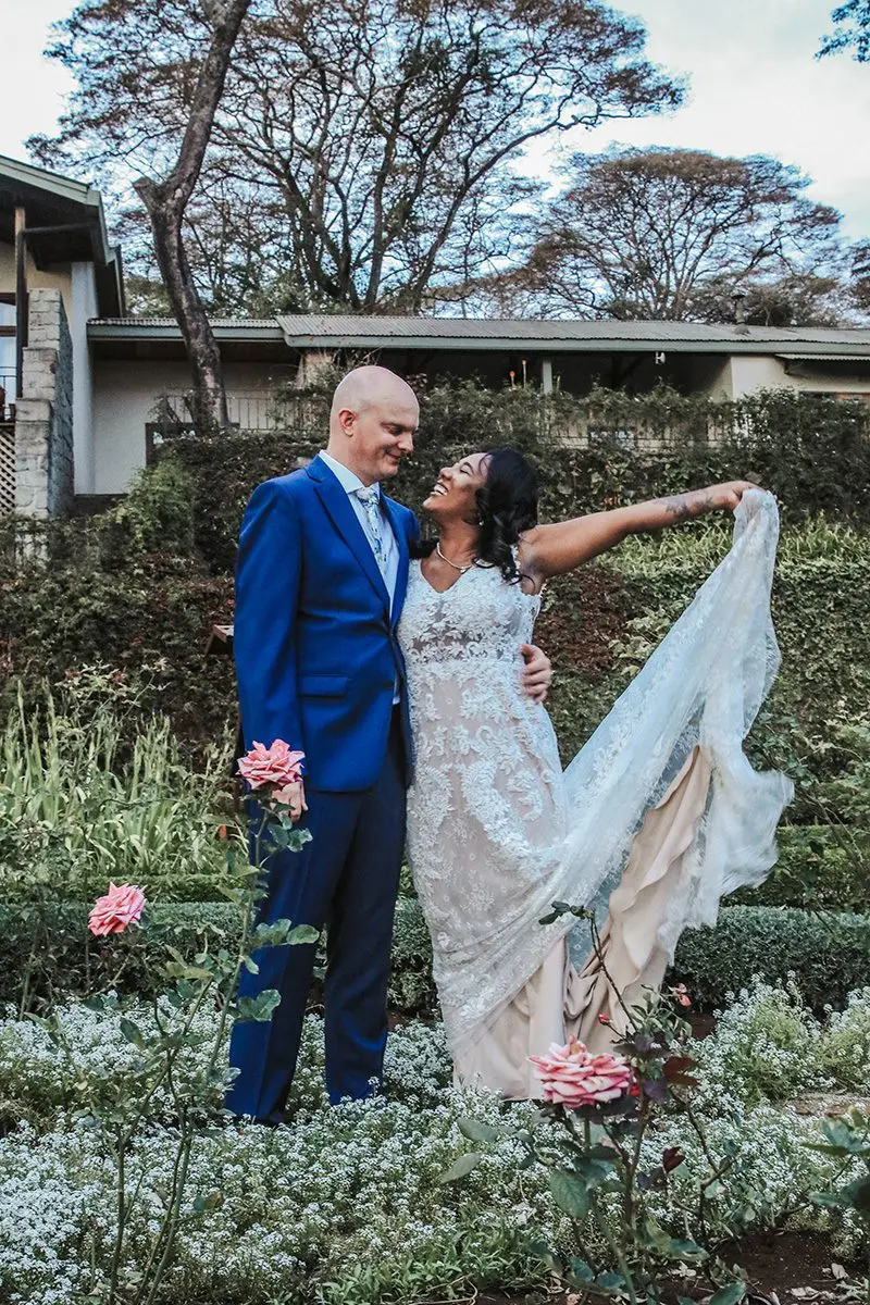 Bride twirling her veil beside the groom in a rose garden at Gibb's Farm