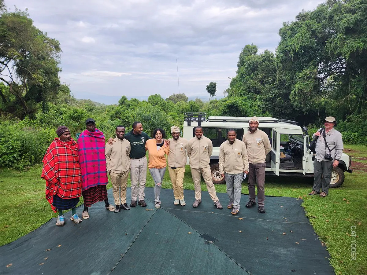 Camp crew and guests posing together in front of a safari vehicle near Ngorongoro
