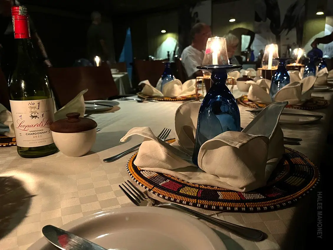 Candlelit dinner table with folded napkins, wine glasses and a bottle of wine
