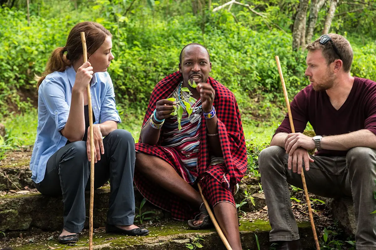 Maasai guide showing a plant to two guests during a medicinal walk at Gibb's Farm