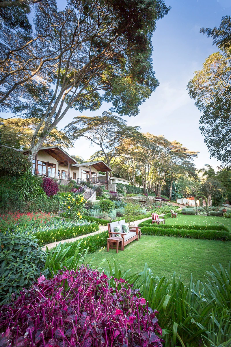 Lush gardens with colorful flowers and lawns below the cottages at Gibb's Farm