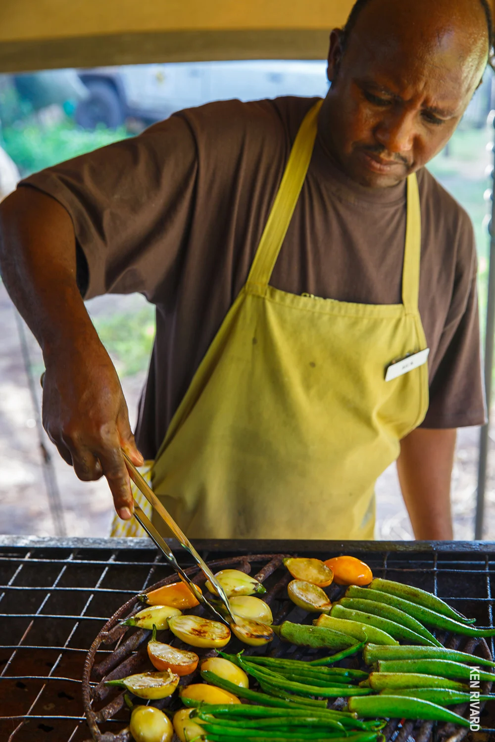 Camp chef grilling okra, peppers and tomatoes over charcoal