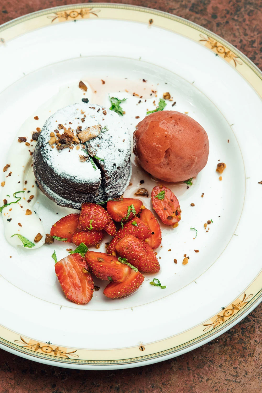 Chocolate lava cake with strawberries, sorbet and cream on a white plate
