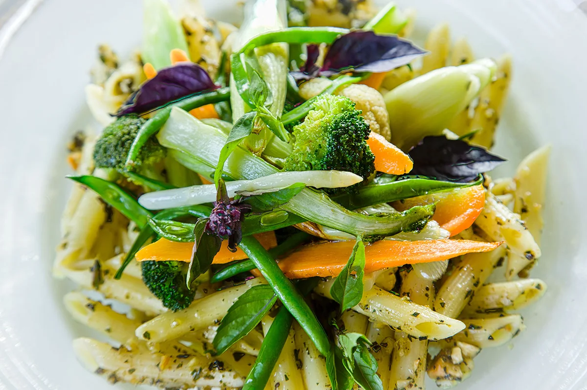 Penne pasta with pesto, broccoli, green beans, carrots and purple basil