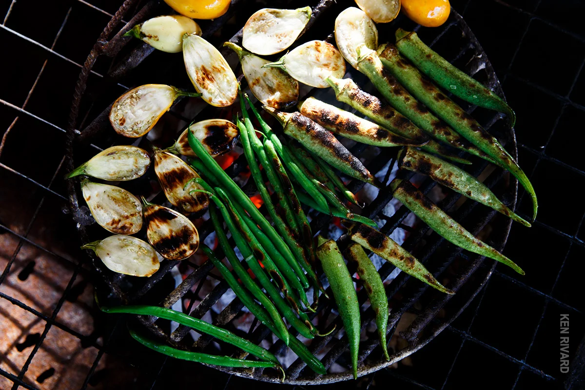 Okra, eggplant and peppers charring on a charcoal grill