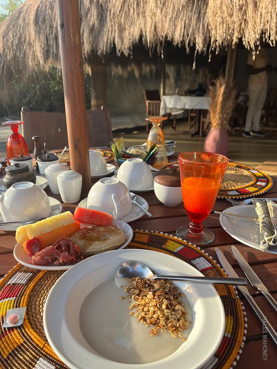 Breakfast of porridge with granola, pancake and fruit on a camp dining table