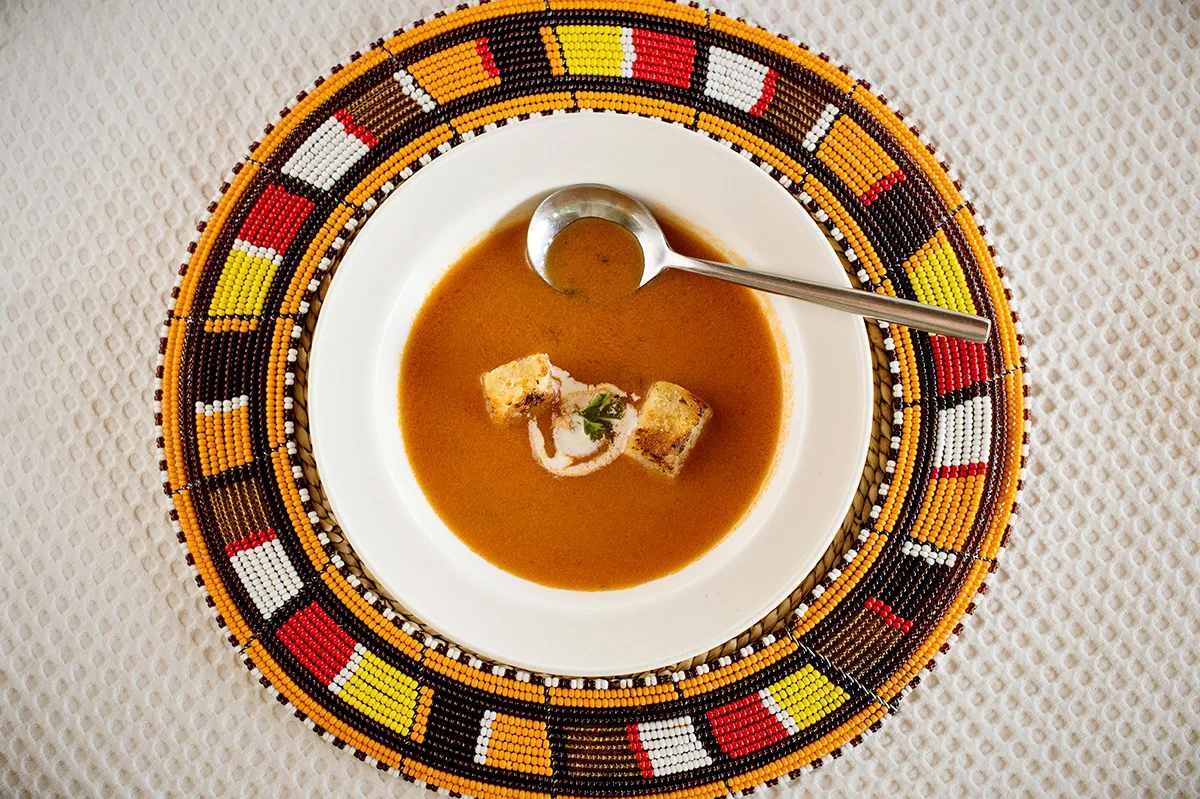 Bowl of tomato soup with croutons on a beaded placemat