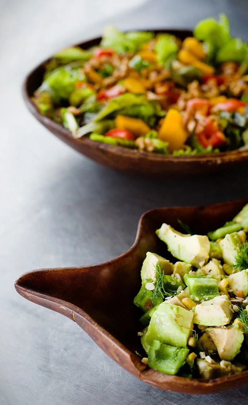 Wooden bowls of green salad and avocado salad with dill