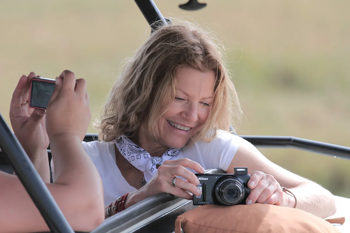 Smiling woman holding a compact camera in a safari vehicle