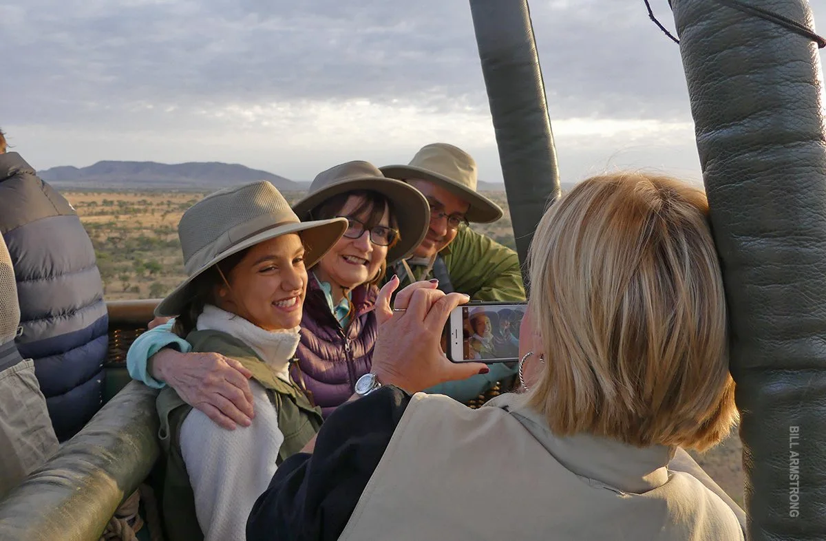 Family posing for a phone photo in a hot air balloon basket over the plains