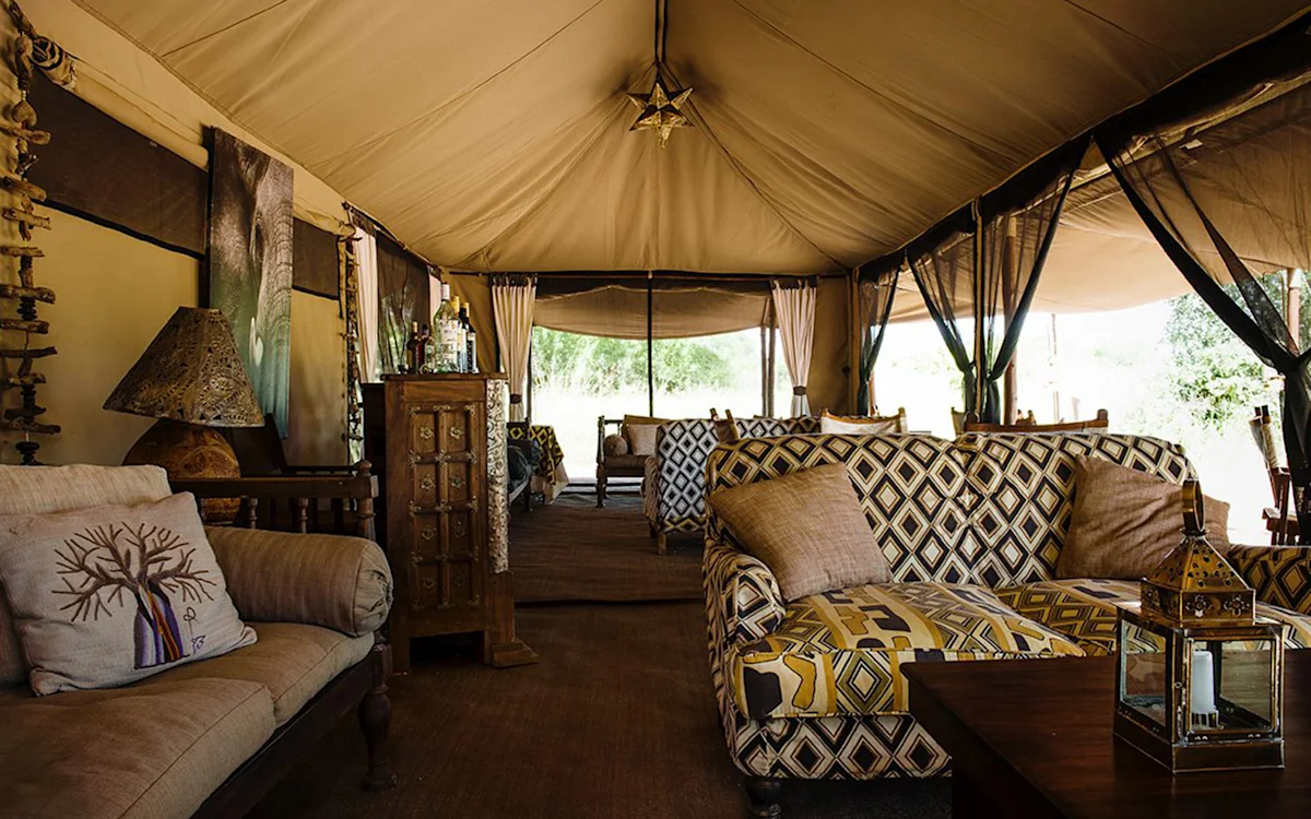 Lounge tent with patterned sofas, lanterns and a wooden cabinet at Tarangire Nyumba